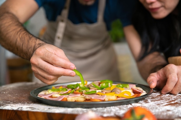 Cara de masa de pizza italiana casera con verduras y salsa cocinada por una pareja amorosa chef en casa en la mesa en la cocina moderna feliz momento familiar juntos