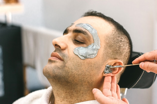 Cara masculina depilación. Barber elimina el vello de la cara del hombre turco.