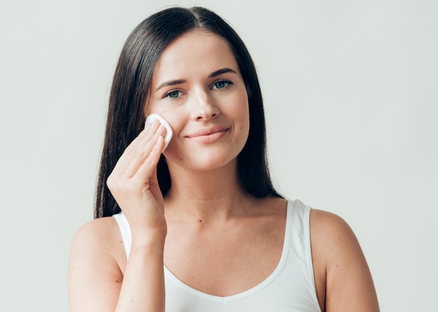 Cara de mujer de almohadilla de algodón quitar maquillaje piel sana maquillaje natural. Tiro del estudio.