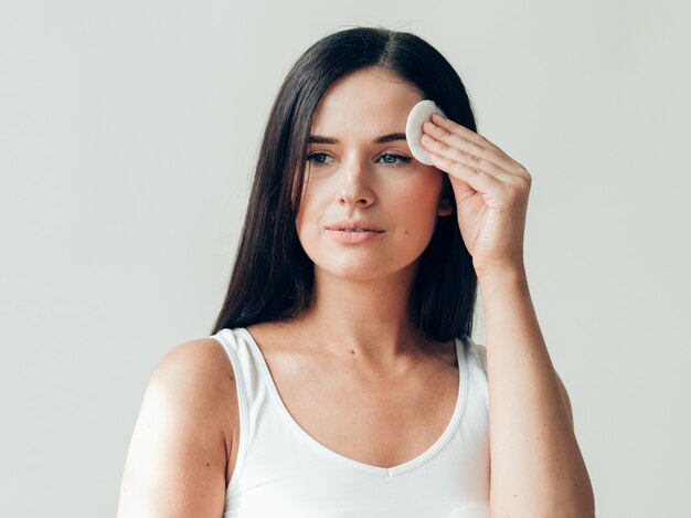 Cara de mujer de almohadilla de algodón quitar maquillaje piel sana maquillaje natural. Tiro del estudio.