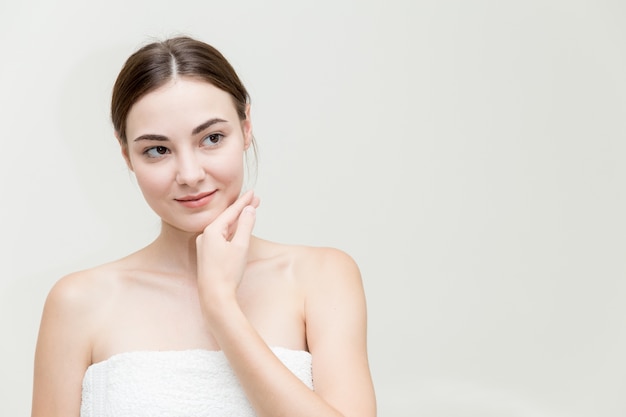 La cara de la mujer de la belleza con la mano presenta su forma de la cara aislada en el estudio blanco