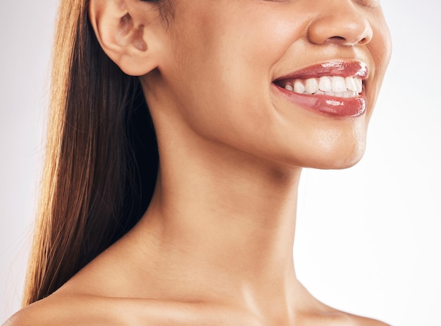 Cara de mujer y blanqueamiento de dientes con sonrisa dental y salud de la piel y brillo de labios sobre fondo blanco Bienestar de la boca atención de salud bucal y carillas de ortodoncia y cuidado cosmético de maquillaje en el estudio