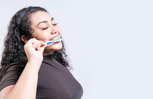 Cara de una mujer joven cepillándose los dientes aislada Concepto de sonrisa oral y dental Mujer sonriente cepillándose las dientes aislada con espacio de copia