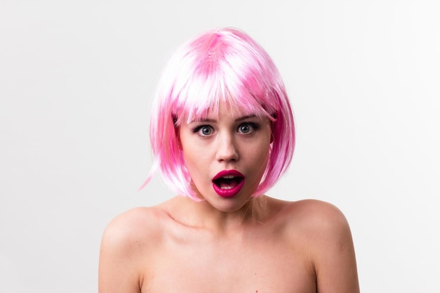 Cara de una mujer joven con maquillaje brillante sobre un fondo rosa con el pelo recogido en una cola de caballo suave