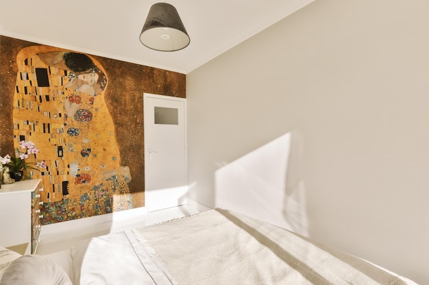 La cara de una mujer pintada en la pared junto a una cama en un dormitorio con sábanas y almohadas blancas