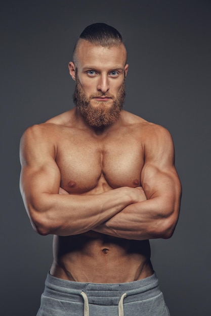 Cara musculoso de barba com braços cruzados isolados em fundo cinza.