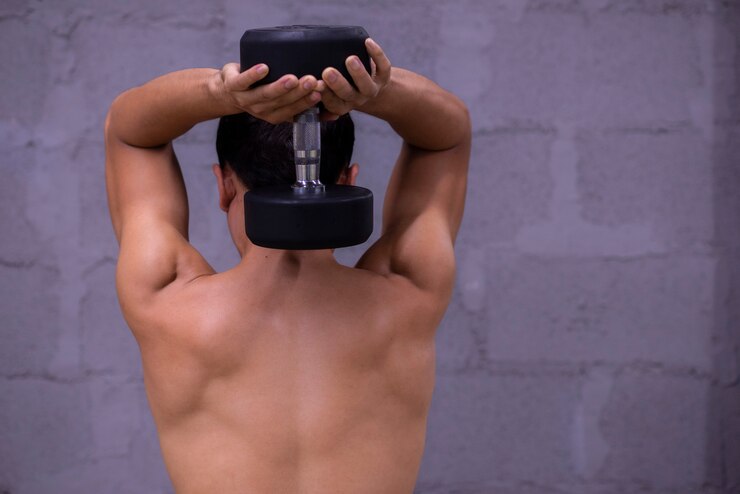 Foto cara musculoso fisiculturista fazendo exercícios com halteres