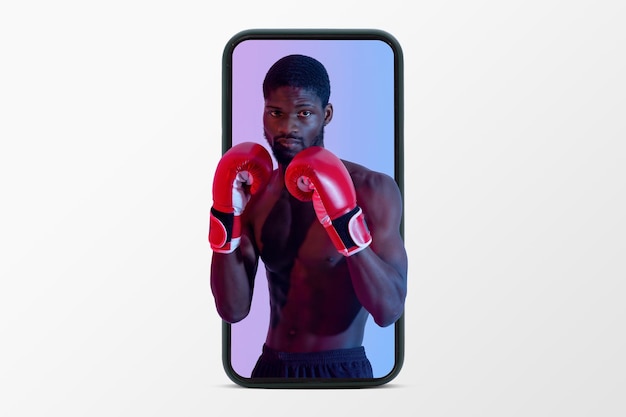 Cara negro musculoso confiante com torso nu e luvas de boxe na tela do telefone