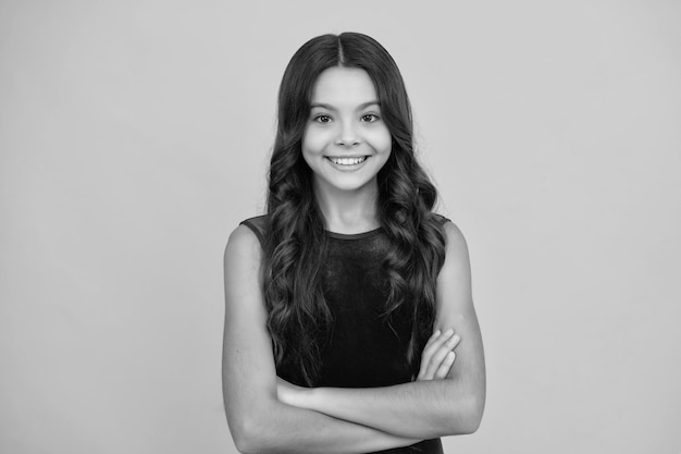 Cara de niña feliz emociones positivas y sonrientes Niña adolescente con los brazos cruzados aislada sobre fondo amarillo Retrato de estudio de niño con espacio de copia simulado