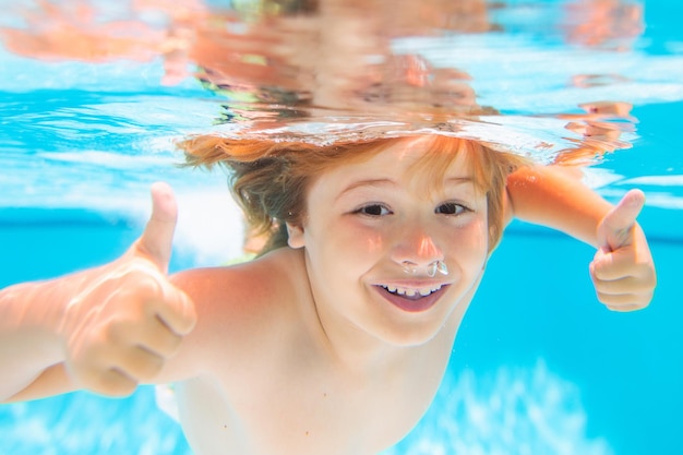 Cara de niño bajo el agua con los pulgares hacia arriba niño joven nadar y bucear bajo el agua retrato bajo el agua nadando