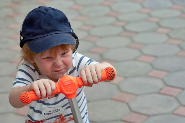 La cara de un niño con una emoción brillante en la cara de un scooter.