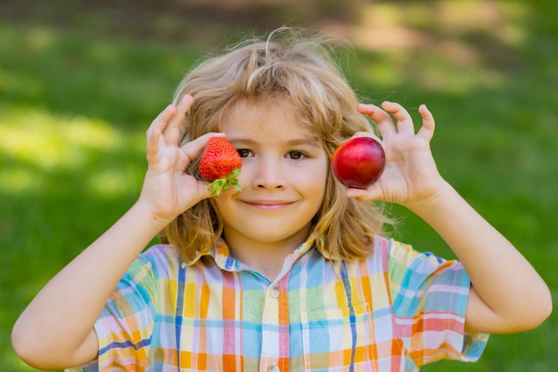 Cara de niño de verano Niño recogiendo y comiendo fresa madura Niño feliz sosteniendo frutas frescas fresa de bayas Fresas de bayas orgánicas saludables fruta temporada de verano