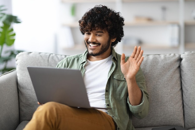 Cara oriental positivo tendo chamada de vídeo usando o computador em casa