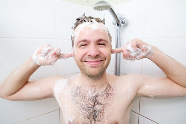 Cara peludo jovem lavando no banheiro Um homem gosta de lavar a cabeça e as orelhas