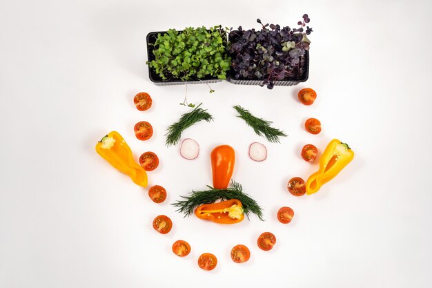 La cara de una persona hecha de verduras sobre un fondo blanco.