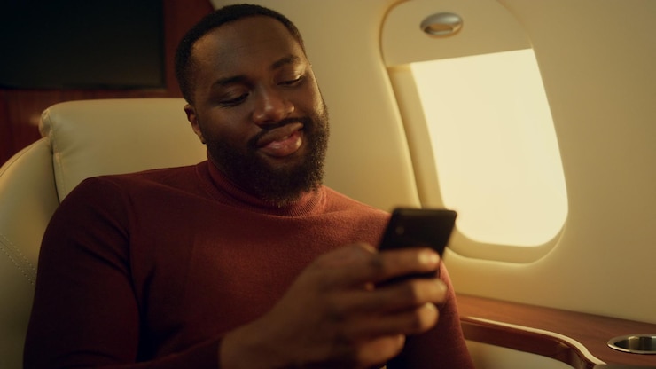 Foto cara positivo conversando on-line em viagem de avião mãos segurando um smartphone closeup