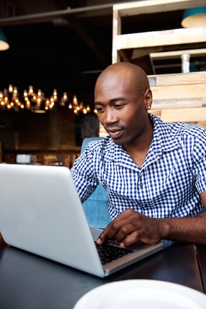 Cara preta trabalhando no laptop em um café