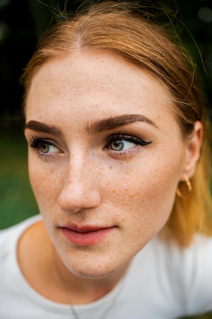 Cara en primer plano de una joven roja con pecas de jengibre con piel perfecta y sana con pecas