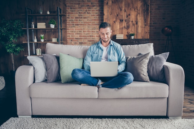 cara relaxando sentado confortável sofá pernas cruzadas navegando no caderno