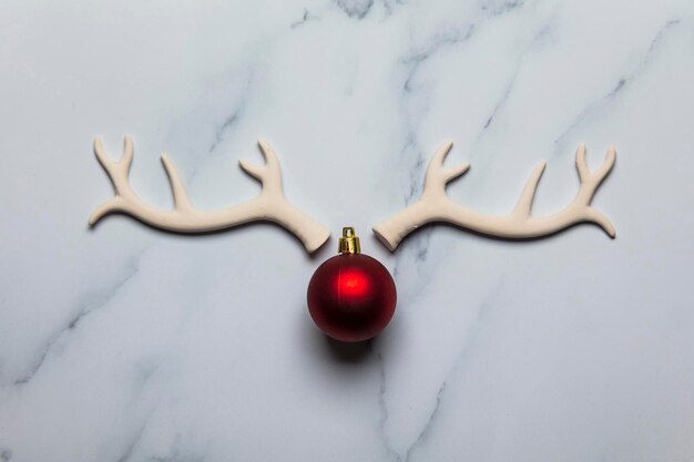 Cara de reno de Navidad hecha de cuernos y adornos sobre un fondo de mármol