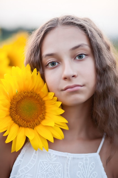 Cara de retrato de niña adolescente en campo de girasoles.