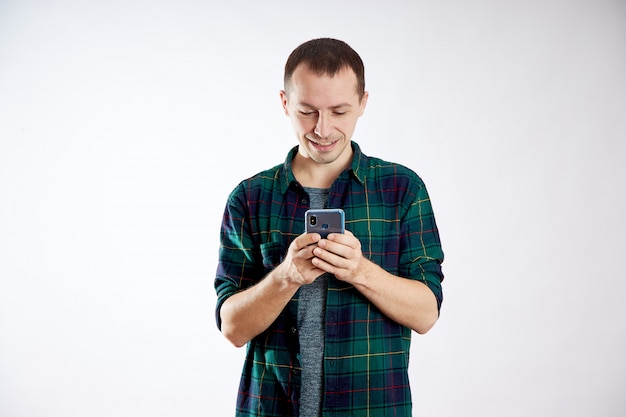 Cara segura o telefone nas mãos e aponta para ele com o dedo. Um homem toca em seu telefone e assiste a vídeos, redes sociais