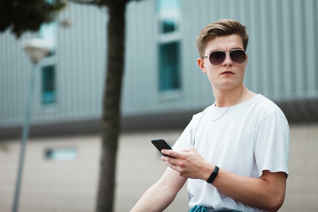 Cara sentado em um banco com um smartphone