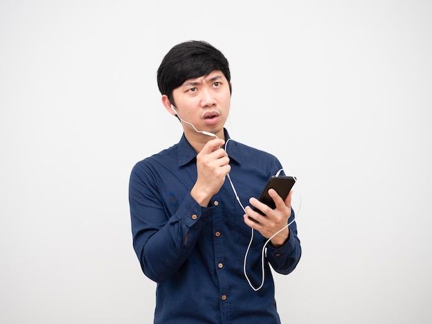 Cara séria de homem asiático falando com fone de ouvido segurando o mobiilephone na mão sobre fundo branco