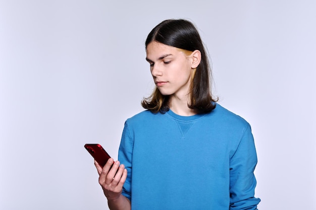 Cara sério com smartphone na mão no fundo claro do estúdio