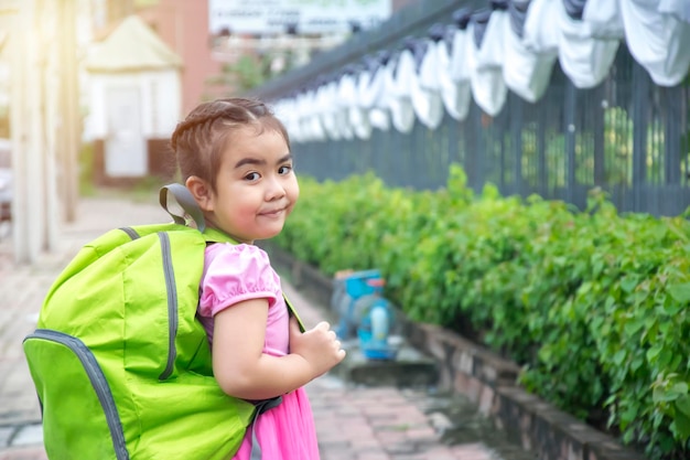 La cara sonriente de Asia con una camisa rosa y una mochila verde. La educación es importante para sentar las bases de la vida. Los niños van felices a la escuela y se esfuerzan por aprender cosas nuevas.