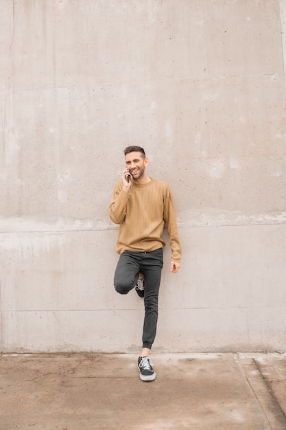 Cara de sonrisa feliz de hombre guapo con soporte para smartphone aislado sobre fondo gris