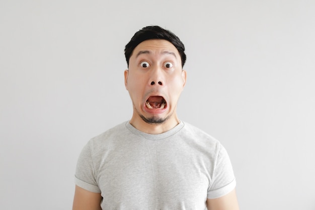 Cara sorprendida del hombre asiático en camiseta gris y fondo gris.