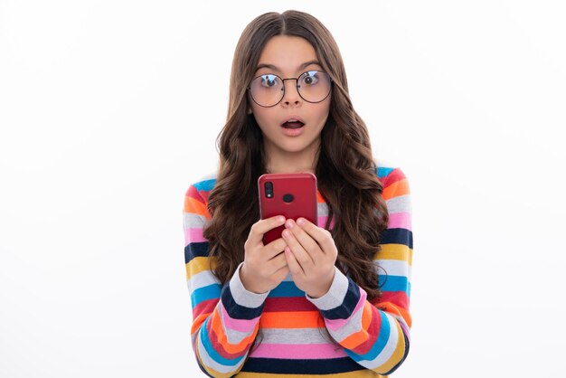 Cara sorprendida sorpresa emociones de chica adolescente Closeup retrato de linda chica adolescente mediante teléfono móvil celular aplicación web aislado sobre fondo blanco.