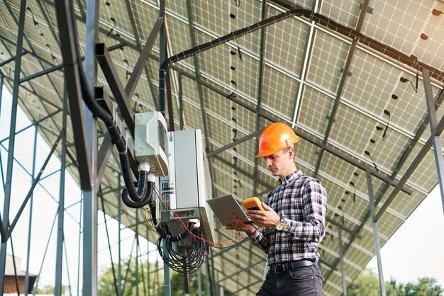 Cara sorridente com laptop e sensor no fundo da estação de energia solar