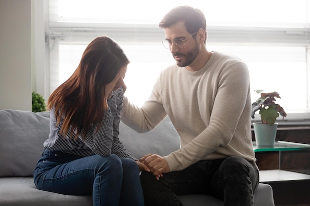 Cara tranquiliza a amada garota segura a mão dela mostrando amor e cuidado sincero amigo próximo apoia namorada compartilha problemas marido reconfortante esposa casal passa pelo conceito de problemas de saúde de infertilidade