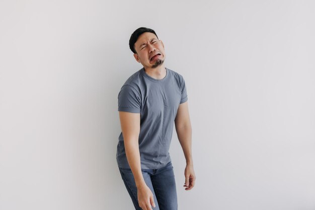 Foto cara triste e engraçada homem asiático de camisa azul chorando isolado em branco