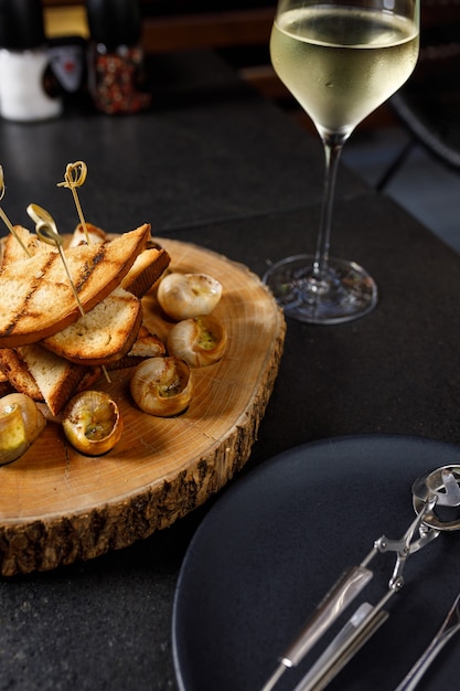 Foto caracoles al horno con aceite de ajo y hierbas sobre una plancha de madera