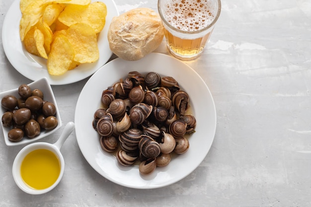 Caracoles hervidos con aceitunas de pan de oso y papas fritas en azul