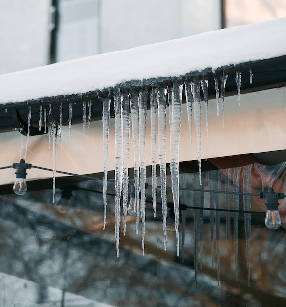 Los carámbanos derretidos cuelgan del techo Concepto de riesgo y daño debido al derretimiento de la nieve y el hielo al aire libre