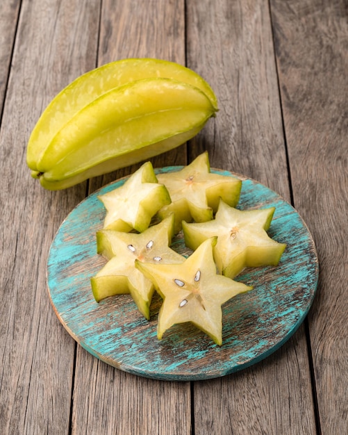 Carambolas con rodajas en un tablero sobre mesa de madera