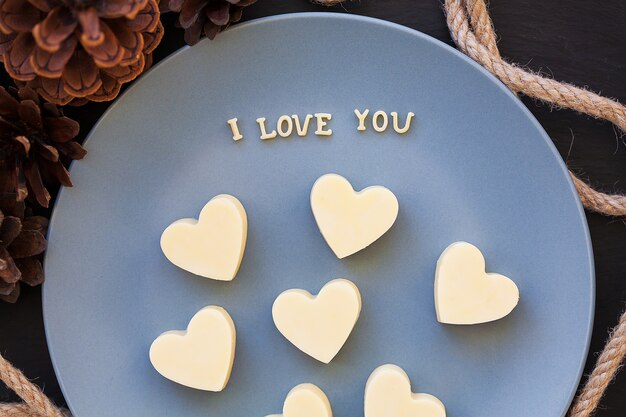 Caramelo de chocolate blanco en el corazón, me encanta escribir en un plato azul con conos