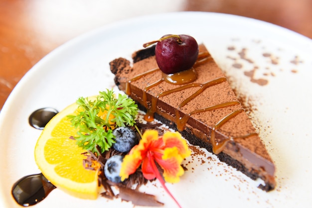 Caramelo de pastel de chocolate con cereza y fruta en la placa blanca.