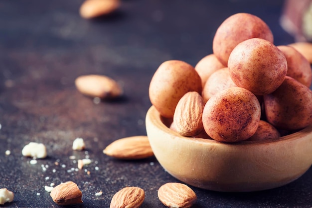 Caramelos de almendras redondas de mazapán en un tazón de madera en el enfoque selectivo de la mesa oscura