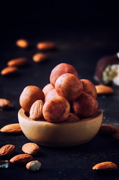 Caramelos de almendras redondas de mazapán en un tazón de madera en el enfoque selectivo de la mesa oscura