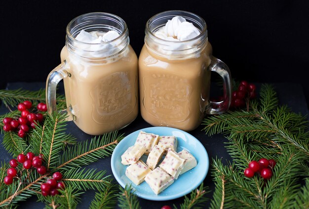 Caramelos y cacao con malvaviscos sobre un fondo negro con chocolate blanco