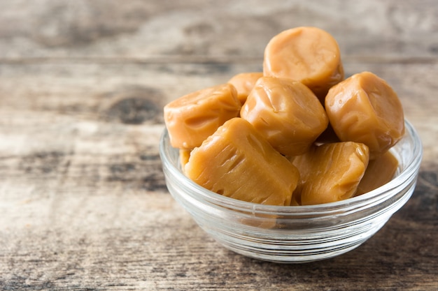 Caramelos de caramelo en un recipiente de cristal en la mesa de madera