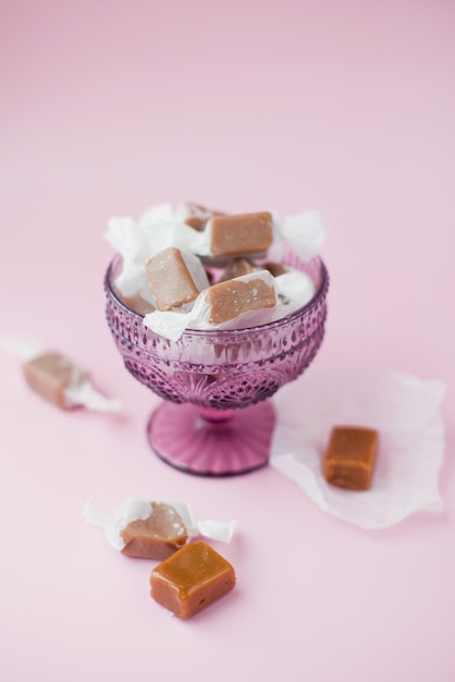 Caramelos de caramelo en recipiente de vidrio morado