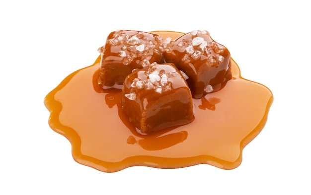 Caramelos de caramelo con salsa de caramelo y sal aislado en blanco