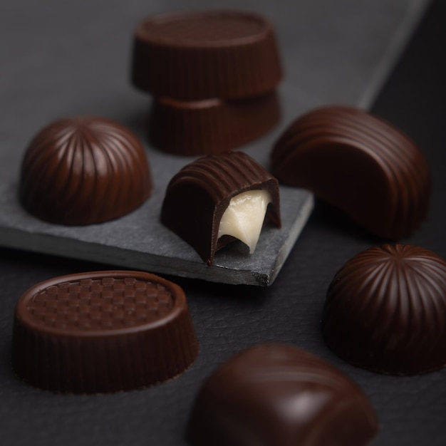Caramelos de chocolate amargo oscuro en una caja. El postre dulce son los dulces. Surtido de dulces de lujo