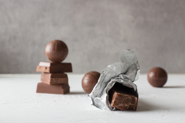 Caramelos de chocolate y barras mordidas en la tabla blanca. Un lugar para el texto.